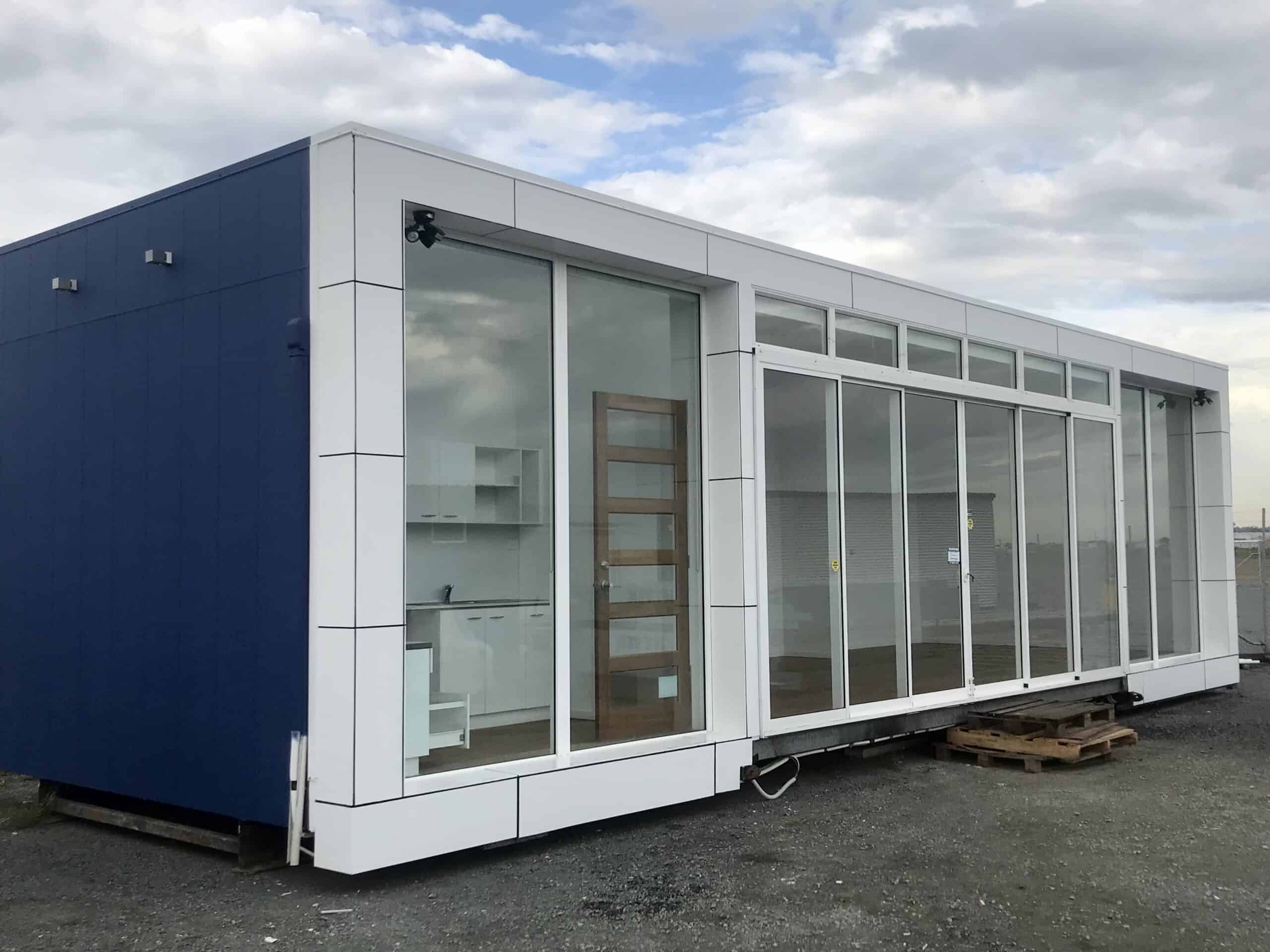 External glass fronted marketing suite with a blue wall