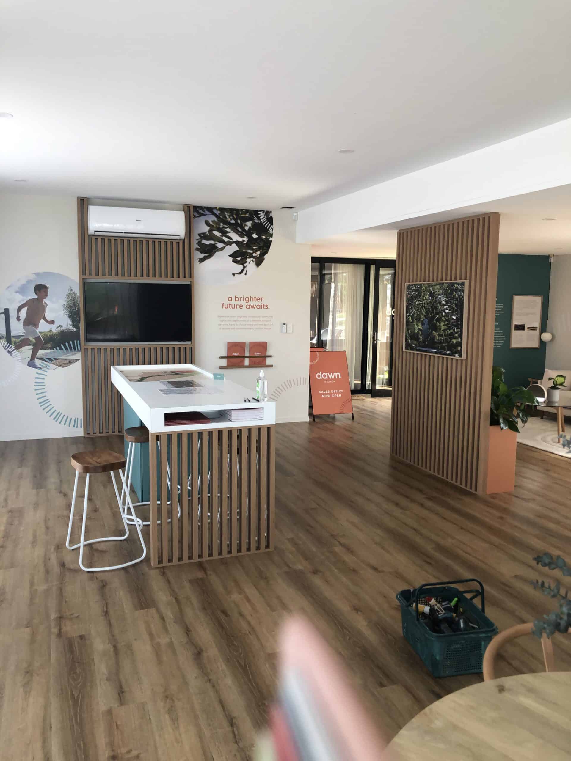 The inside of a marketing showroom with a wooden floor and wall panels.